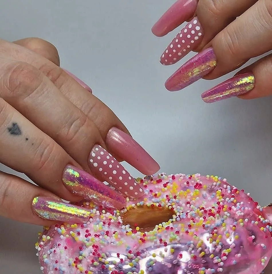 Lange roze nagels met witte stippen en een parelmoerglans